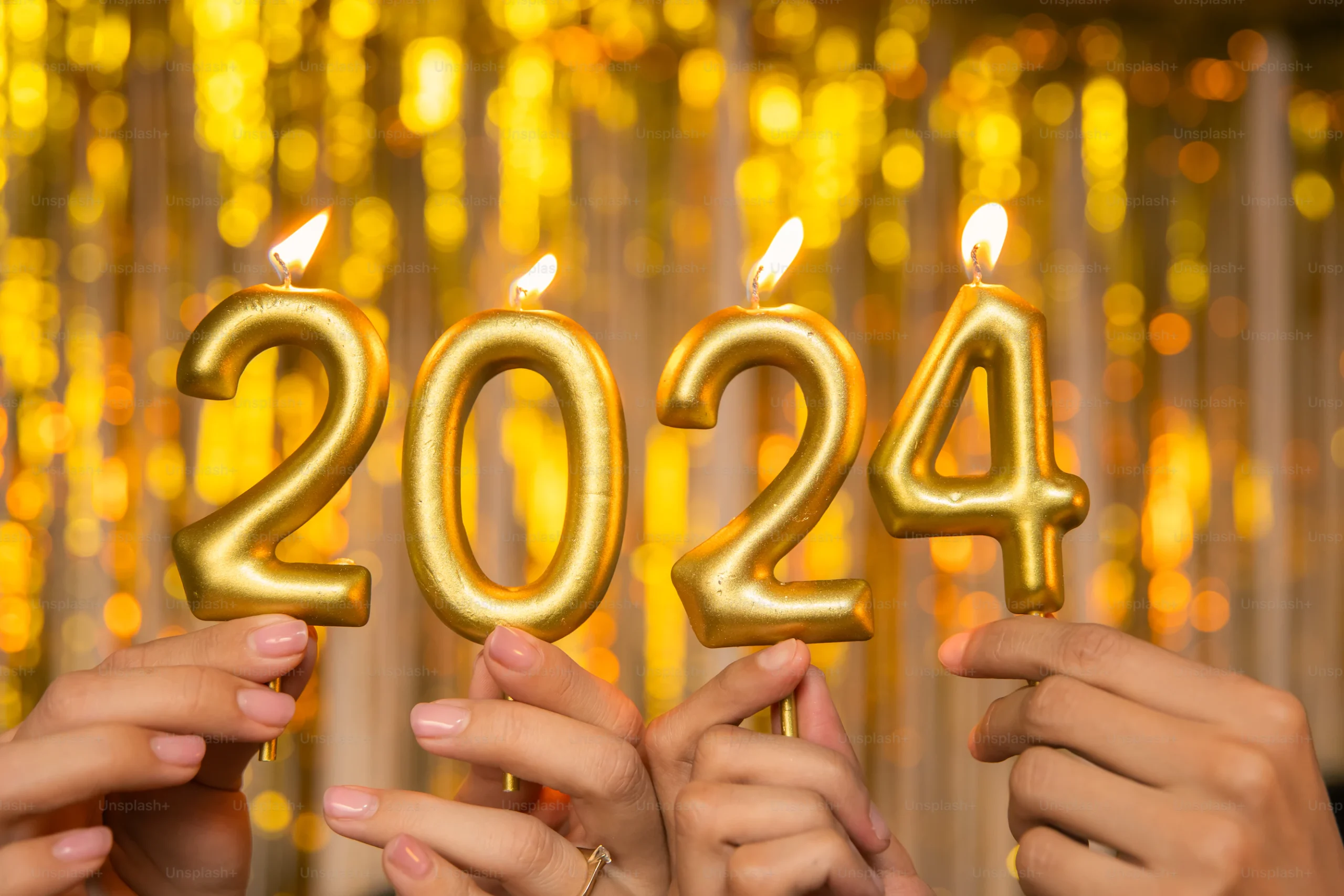 A group of people holding candles in the shape of numbers 2024 on new year eve party
